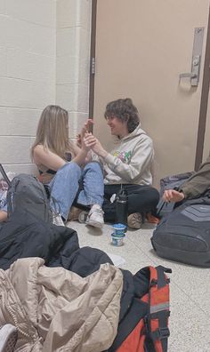 several people sitting on the floor with their luggage