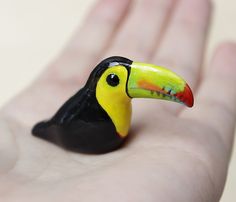 a small toy toucan sitting on someone's hand