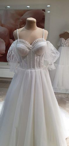 a white wedding dress on display in a store window with mannequins behind it