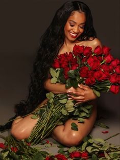 a woman sitting on the ground with roses in her lap and holding it up to her chest