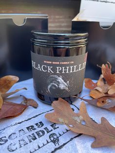 a jar of black phillip sitting on top of a table next to some leaves and a knife