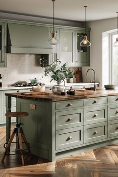 a large kitchen with green cabinets and wooden flooring, an island in the middle