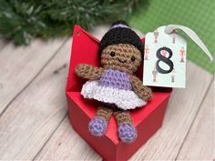 a small crocheted doll in a red box with a price tag on it