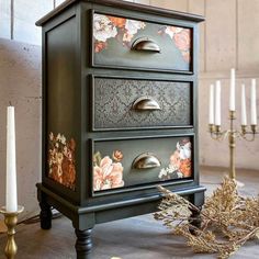 an old dresser with flowers painted on the drawers and candles in front of it,