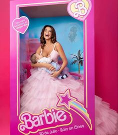 a woman in a pink dress is holding a baby and posing for a photo with the caption barbie