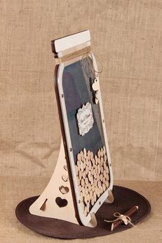 a bottle with corks attached to it sitting on top of a wooden stand next to a brown ribbon