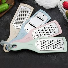 three graters sitting on top of a table next to some vegetables and peppers