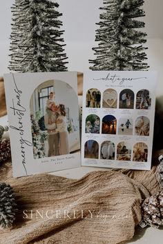 two christmas cards sitting on top of a table next to pine cones and fir trees