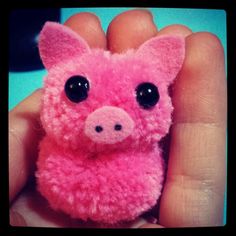 a small pink pig with big eyes in someones hand and it's face