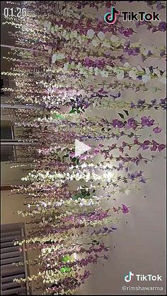 purple and white flowers are hanging from the ceiling in front of a wall with mirrors