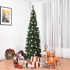 a christmas tree is surrounded by presents and deer figurines in front of it