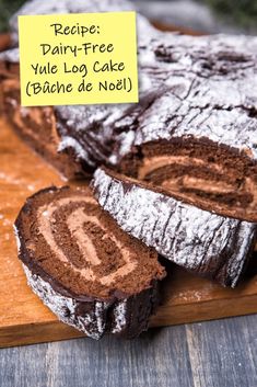 a wooden cutting board topped with slices of chocolate cake next to a sign that says recipe dairy - free yule log cake bake de noel