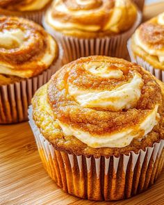 several cinnamon rolls sitting on top of a wooden table next to other muffins