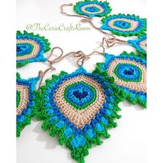 three crocheted necklaces are displayed on a white surface, one is blue and the other is green