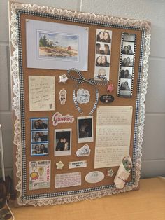 a bulletin board with pictures, magnets and papers attached to it on a desk