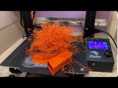 an orange piece of wire sitting on top of a black table next to a machine