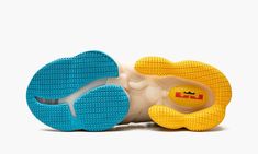 a pair of shoes with yellow and blue soles on top of each other, against a white background