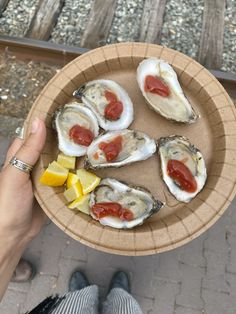 a person holding a plate with oysters on it