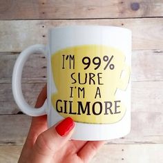 a woman's hand holding a coffee mug with the words i'm 99 % sure i'm a glimore on it