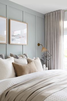 a bed with two framed pictures on the wall above it, and pillows in front of them