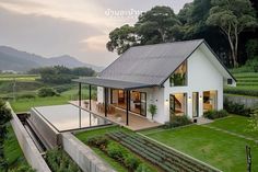 an aerial view of a house in the middle of a lush green field with mountains in the background