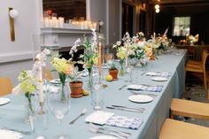 a long table is set with place settings and flowers in vases on the tables