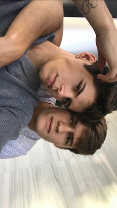 two young men standing next to each other in front of a mirror on the floor