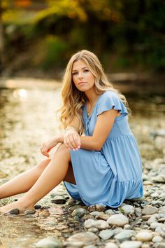 a beautiful woman sitting on top of a river next to rocks