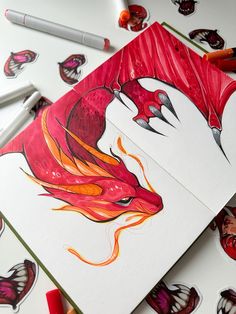 two cards with dragon designs on them next to crayon markers and pencils