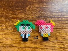 two sheep made out of perler beads sitting on top of a wooden table next to each other