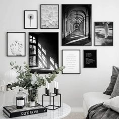 a white living room with black and white pictures on the wall, coffee table in front of it