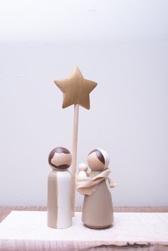 two wooden dolls are standing next to each other with a star on top of them