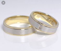 two gold wedding bands with diamonds on each one, sitting side by side against a white background