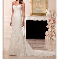 a woman in a white wedding dress standing next to a fireplace with flowers on it