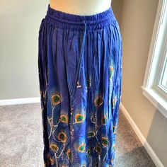 Long Blue Silver Sequin Skirt With Green Orange Purple Peacock Motif (Free Size). Holiday Festivities Or Any Day Fun Wear. 2” Elastic Waistband And Drawstring With Silver Balls For The Finish. Free Size Will Fit Most. The Skirt Measures 35-1/2” In Length, 14” Waist Band That Is Tight So It Will Stretch. 100% Rayon. Hand Wash Separately In Cold Water. New Without Tags. Blue Maxi Skirt For Festivals, Festival Blue Lined Maxi Skirt, Blue Lined Skirt For Festivals, Blue Lined Skirt For Festival, Traditional Blue Flowy Maxi Skirt, Traditional Blue Maxi Skirt, Blue Long Skirt For Festival, Traditional Blue Lined Skirt, Traditional Blue Flowy Skirt