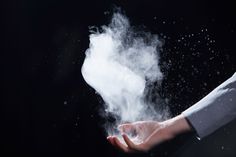 a person holding something in their hand with white powder coming out of the top and bottom