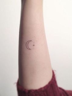 a woman's arm with a small crescent tattoo on it