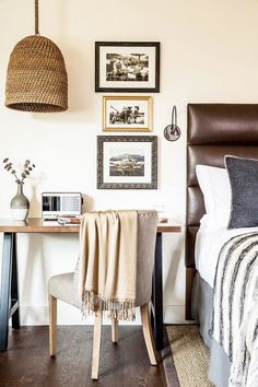 a bed room with a neatly made bed next to a desk and pictures on the wall