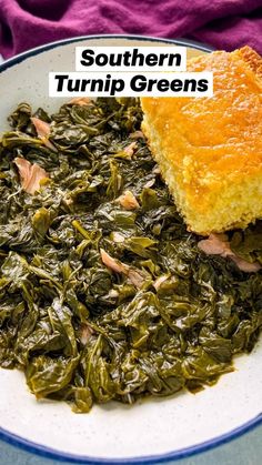 a white plate topped with greens next to a piece of bread