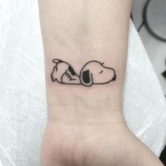 a small snoopy dog tattoo on the wrist