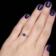 a woman's hand with black nail polish and a blue ring on her finger