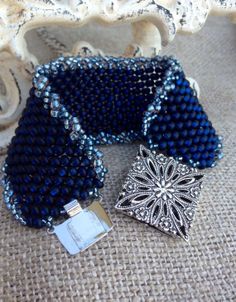 two blue beaded purses sitting on top of a piece of cloth next to each other