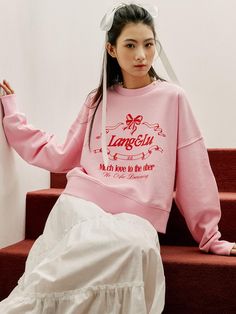 This piece of clothing is a pullover sweatshirt with a crew neckline and long sleeves, featuring a relaxed fit that suggests comfort and casual wear. The design on the front includes a decorative graphic with a central motif and text, surrounded by an ornate frame with a bow on top. The garment has ribbed cuffs and a ribbed hem to provide a snug fit at the wrists and waist. The overall design has a youthful and playful aesthetic, with a touch of elegance from the graphic elements.- The sweatshirt's design includes a logo-like graphic that gives it a branded appearance.- The text within the design adds a message that implies affection and a dreamy sentiment.- The structure of the sweatshirt suggests it's made for a unisex fit, which can appeal to a wide range of customers. Playful Aesthetic, Applique Sweatshirt, Lace Print, Graphic Elements, Ornate Frame, W Concept, Pink Sweatshirt, Sweatshirt Designs, Fashion Details