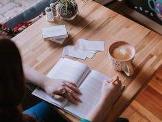 a person sitting at a table with an open book and cup of coffee in front of them