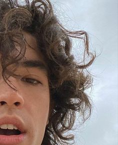 a close up of a person with curly hair on his head and one eye open