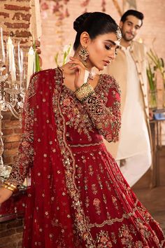 a woman in a red lehenga standing next to a man