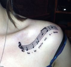 a woman's chest with musical notes on it and the words love is written in cursive writing