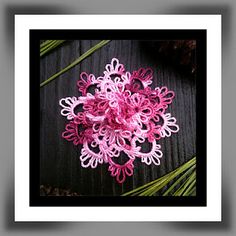 a pink and white flower sitting on top of a wooden table