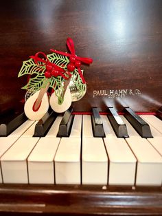 a christmas decoration sits on top of an old piano keyboard with bells and holly berries