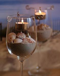 two wine glasses filled with sand and sea shells